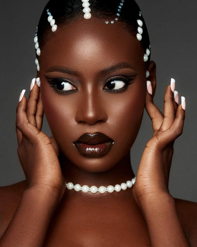 Glamorous studio portrait of a woman adorned with pearl jewelry and bold makeup.
